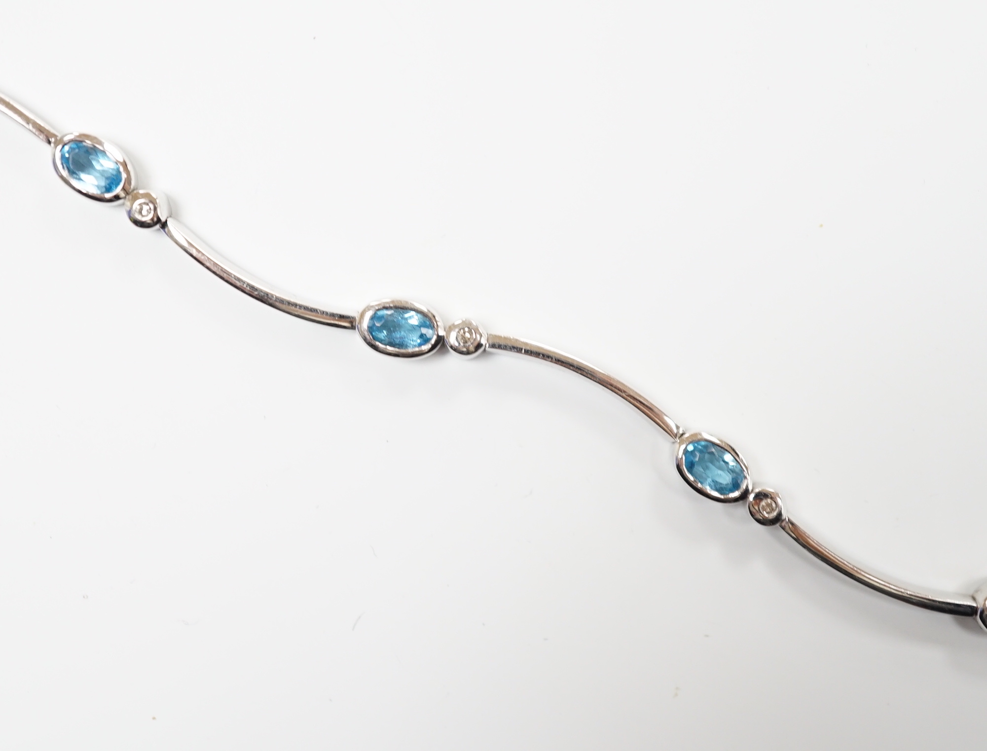 A modern 9ct white gold blue topaz and diamond chip set bracelet, 18.5cm, gross weight 9.1 grams.